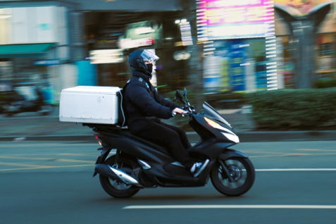 a-man-riding-a-scooter-with-a-box-on-the-back-of-it.jpg a man riding a scooter with a box on the back of it